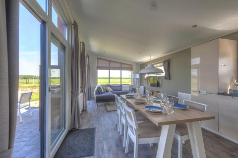 Luminoso comedor y sala de estar en el lodge Pavilion de Poort van Zeeland, Países Bajos, con vista rural.
