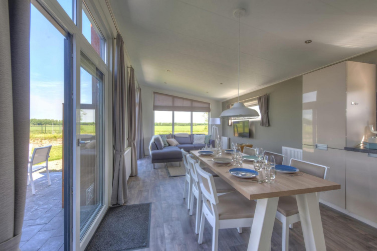 Luminoso comedor y sala de estar en el lodge Pavilion de Poort van Zeeland, Países Bajos, con vista rural.