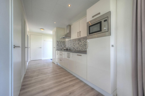 Cocina moderna con muebles blancos y salpicadero de mosaico en Pavilion de Poort van Zeeland, Países Bajos.