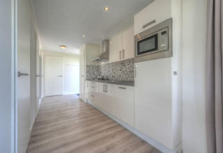 Cocina moderna con muebles blancos y salpicadero de mosaico en Pavilion de Poort van Zeeland, Países Bajos.