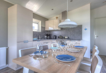 Sala da pranzo con cucina moderna in un lodge al Pavilion di Poort van Zeeland, Paesi Bassi, tavola per sei.