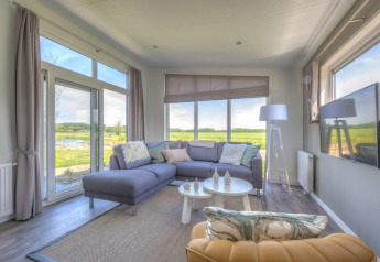 Lichte, moderne woonkamer in een lodge bij Pavilion Poort van Zeeland, Nederland, met grote ramen en uitzicht.