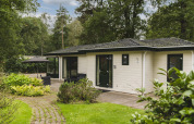 Lodge natural en Bospark Markelo, Países Bajos, rodeado de árboles y vegetación, con zona de terraza.