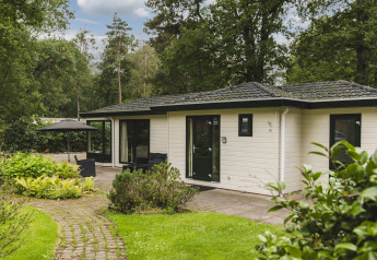 Lodge nature à Bospark Markelo aux Pays-Bas, entouré de verdure et arbres, avec terrasse extérieure.