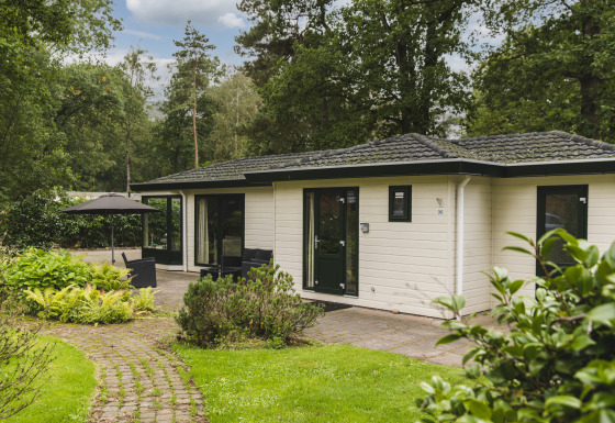 Natuurlodge bij Bospark Markelo in Nederland, omgeven door groen en bomen met terras en zitgedeelte.