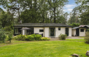 Lodge natural en Bospark Markelo, Países Bajos, rodeada de vegetación y bosque con jardín cuidado.