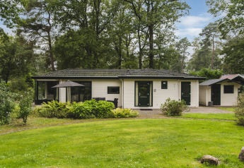 Lodge natural en Bospark Markelo, Países Bajos, rodeada de vegetación y bosque con jardín cuidado.