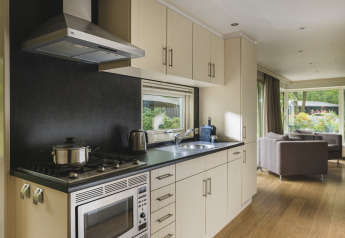 Cocina moderna y sala de estar en una Nature lodge en Bospark Markelo, Países Bajos, con vista al jardín.