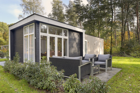 Modern tiny house at Bospark Markelo in the Netherlands with outdoor seating and surrounded by nature.