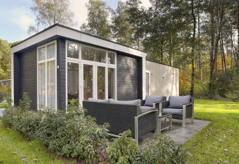 Moderne tiny house bij Bospark Markelo in Nederland met buitenterras, omgeven door bomen en natuur.