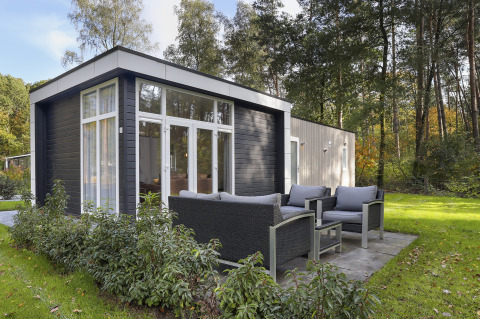 Moderne tiny house ved Bospark Markelo i Holland med udendørs siddeområde i frodigt, grønt miljø.