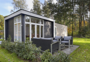 Moderne tiny house ved Bospark Markelo i Holland med udendørs siddeområde i frodigt, grønt miljø.