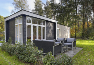 Moderne tiny house ved Bospark Markelo i Holland med udendørs siddeområde i frodigt, grønt miljø.