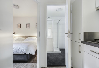 Schlafzimmer, Badezimmer und Küche im Tiny House im Bospark Markelo, Niederlande, mit moderner Einrichtung.
