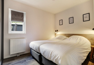 Bedroom in Tiny House at Bospark Markelo, Netherlands, featuring twin beds and a cozy minimalist decor.