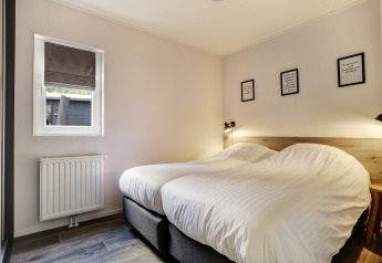 Slaapkamer in Tiny House bij Bospark Markelo, Nederland, met twee aparte bedden en een moderne stijl.