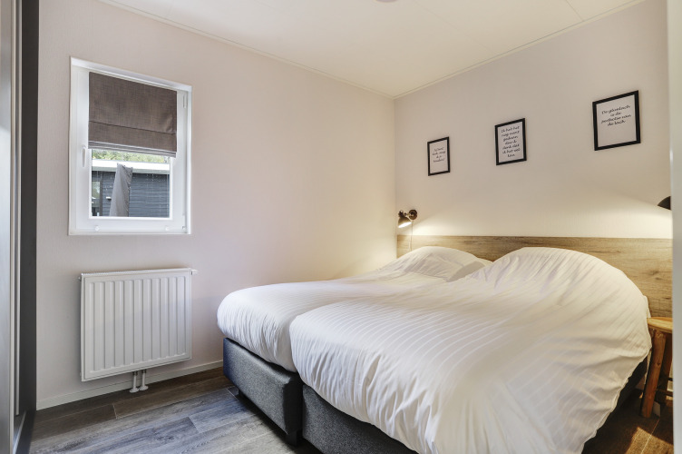 Dormitorio en Tiny House en Bospark Markelo, Países Bajos, con dos camas individuales y decoración acogedora.