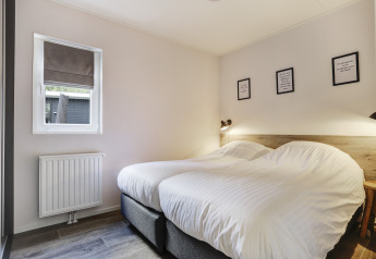 Dormitorio en Tiny House en Bospark Markelo, Países Bajos, con dos camas individuales y decoración acogedora.