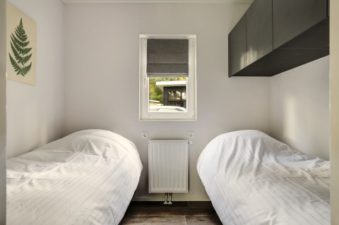 Small bedroom with two single beds, window, and minimalist decor in Tiny House at Bospark Markelo, Netherlands.