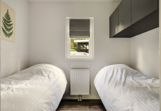 Small bedroom with two single beds, window, and minimalist decor in Tiny House at Bospark Markelo, Netherlands.
