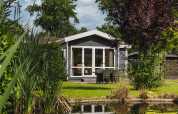 Piccola casa Forest Lodge Wellness accanto a uno stagno nel verde a Bospark Markelo, Paesi Bassi.