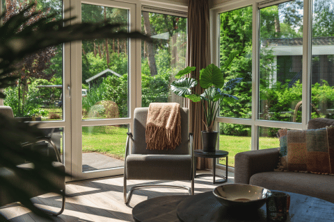 Woonkamer met grote vensters en zicht op de tuin in Forest Lodge Wellness, Bospark Markelo, Nederland.