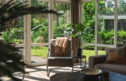Sala de estar con grandes ventanas y vista al jardín en Forest Lodge Wellness, Bospark Markelo, Países Bajos.