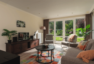 Woonkamer van Forest Lodge Wellness in Bospark Markelo, Nederland, met grote ramen en tuinzicht.