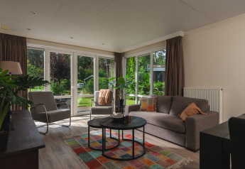 Helles, modernes Wohnzimmer in der Forest Lodge Wellness, Bospark Markelo, mit Blick auf Garten.