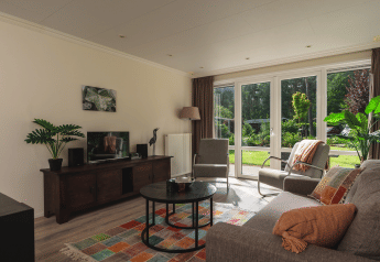 Sala luminosa en Forest Lodge Wellness, Bospark Markelo, con grandes ventanas y una alfombra colorida.