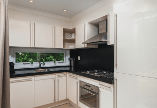 Cocina moderna y luminosa con gabinetes blancos en Forest Lodge Wellness en Bospark Markelo, Países Bajos.