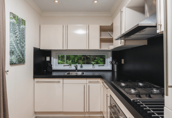 Cucina moderna e compatta al Forest Lodge Wellness, Bospark Markelo, Paesi Bassi, con mobili bianchi.
