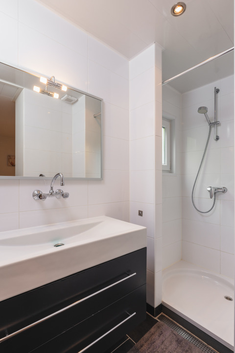 Moderne compacte badkamer met douche, spiegel en zwart wastafelmeubel in Forest Lodge Wellness, Bospark Markelo.