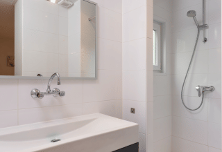 Kleine moderne badkamer met douche, spiegel en zwart meubel in Forest Lodge Wellness, Bospark Markelo.