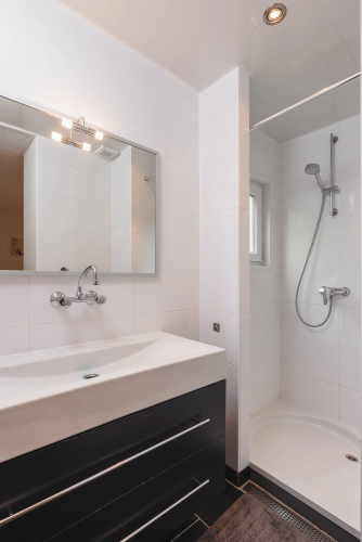 Baño moderno y compacto con ducha, espejo y tocador en Forest Lodge Wellness, Bospark Markelo, Países Bajos.