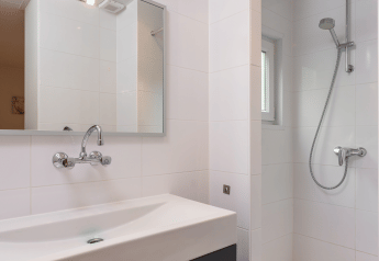 Baño moderno y compacto con ducha, espejo y tocador en Forest Lodge Wellness, Bospark Markelo, Países Bajos.