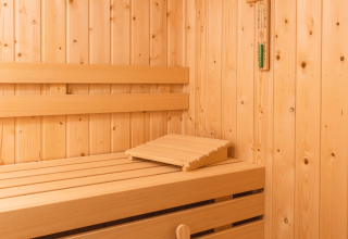 Vista interior de una moderna sauna de madera con bancos y balde en Forest Lodge Wellness, Bospark Markelo.