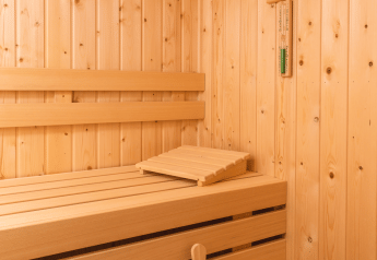 Vista interna di una sauna moderna in legno con panche e secchio al Forest Lodge Wellness, Bospark Markelo.