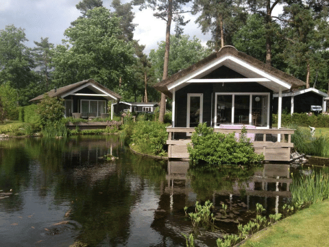 Zwei kleine Lodges am Teich im Grünen, aufgenommen bei Bospark Markelo in den Niederlanden.