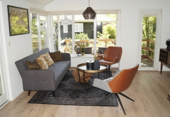 Bright living room at Lodge Meerkoet, Bospark Markelo, Netherlands, with modern decor and large garden windows.