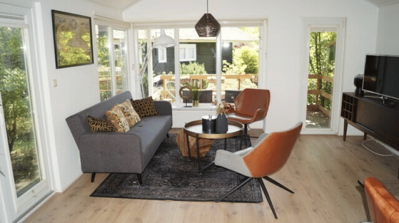 Sala luminosa en Lodge Meerkoet, Bospark Markelo, Países Bajos, con decoración moderna y grandes ventanales al jardín.