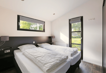 Dormitorio luminoso en la Lodge Meerkoet, Bospark Markelo, Países Bajos, con dos camas individuales.