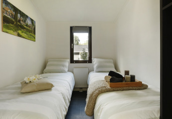 Habitación de glamping acogedora con dos camas individuales, ventana central y decoración moderna.