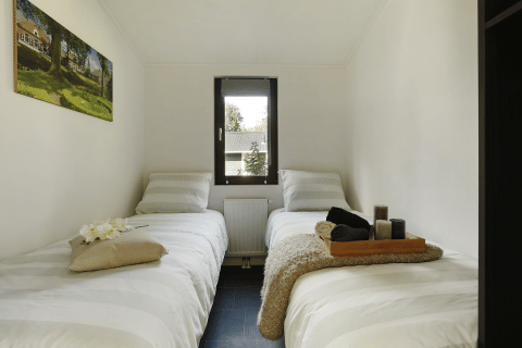 Stanza glamping accogliente con due letti singoli, una finestra centrale e decorazioni moderne.