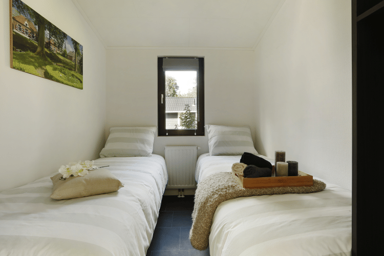 Habitación de glamping acogedora con dos camas individuales, ventana central y decoración moderna.