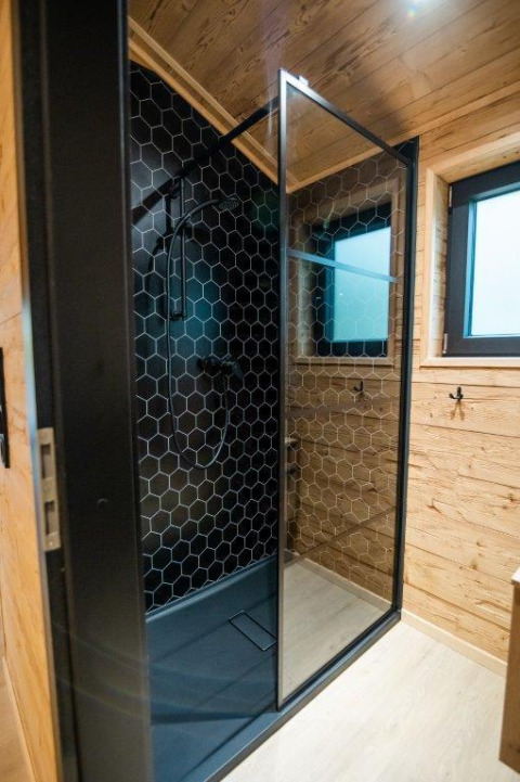 Moderne Duschkabine mit schwarzer Wabenfliesenwand und Holzverkleidung in Terrace Chalet, Bospark Markelo.