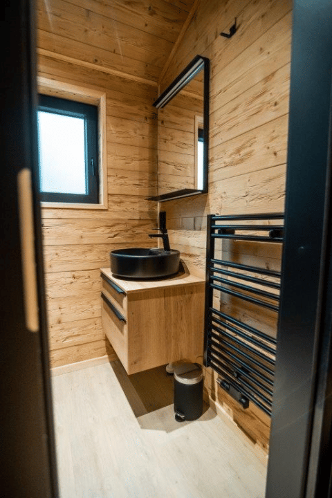 Moderne badeværelse i træ på Terrace Chalet, Bospark Markelo, Nederlandene, med sort håndvask og spejl