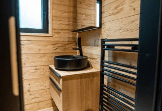 Baño moderno de madera en Terrace Chalet, Bospark Markelo, Países Bajos, con lavabo negro y espejo