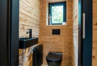 Baño moderno con accesorios negros y paredes de madera en Terrace Chalet en Bospark Markelo, Países Bajos.