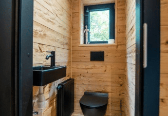 Bagno moderno con rubinetteria nera e pareti in legno presso Terrace Chalet al Bospark Markelo, Paesi Bassi.